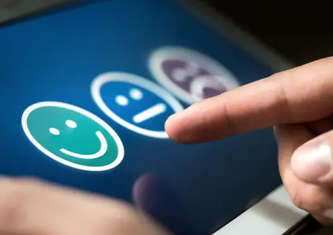 Dedo seleccionando una carita sonriente en una pantalla de valoración